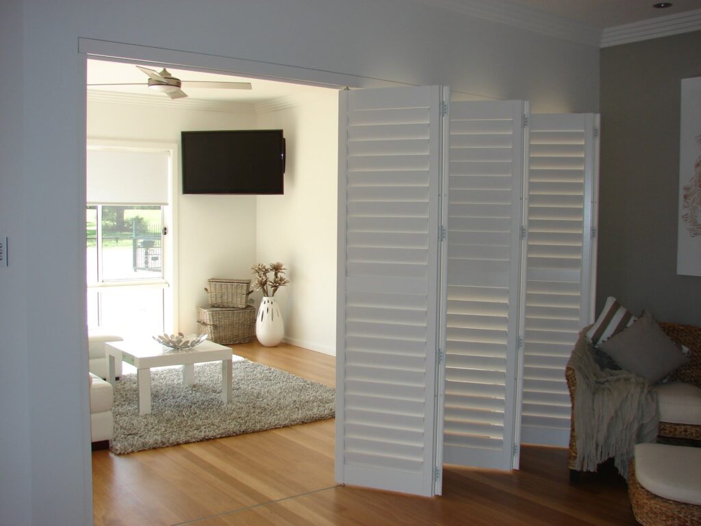 Three white plantation shutter panels used as a folding room divider.