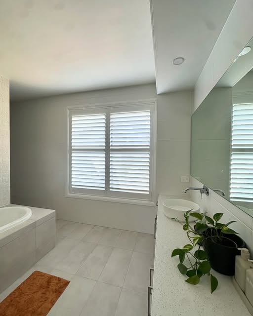 A window is covered with white plantation shutters for privacy
