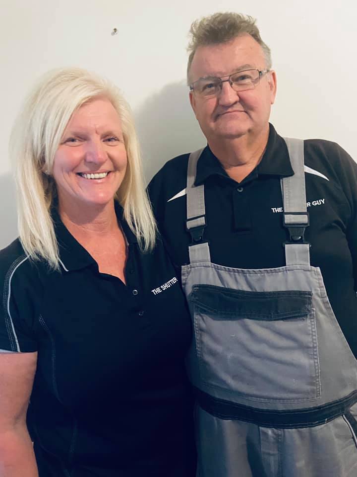 A head-and-shoulders portrait of a smiling blonde woman and a man in grey overalls and black work shirts of The Shutter Guy